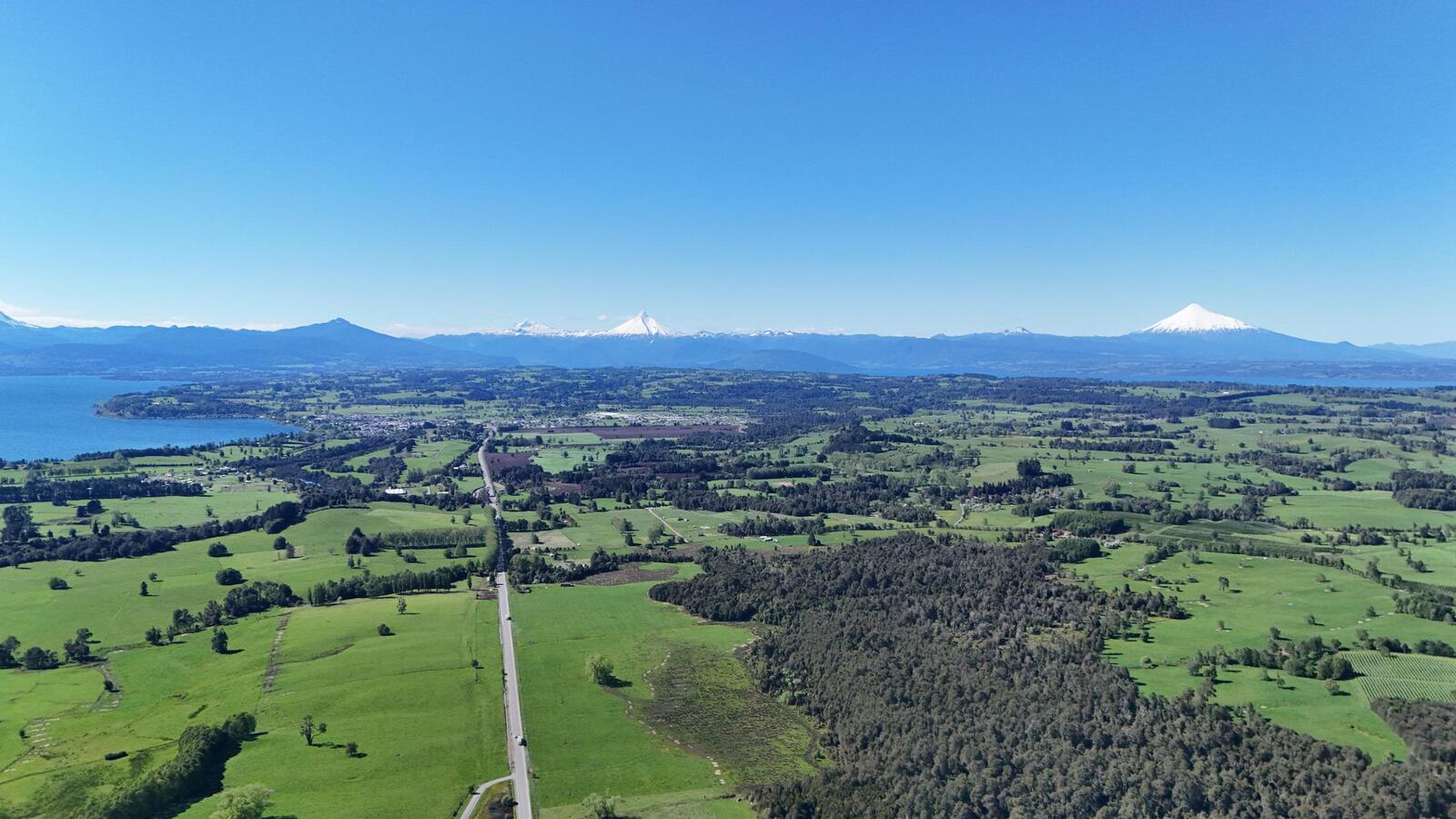 Praderas, un lago y volcanes nevados vistos desde el aire